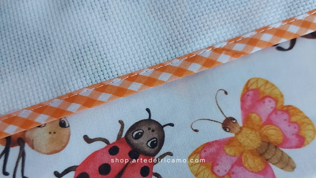 particolare del set asilo con piccoli insetti come farfalle e coccinelle con inserto in tela Aida da ricamare